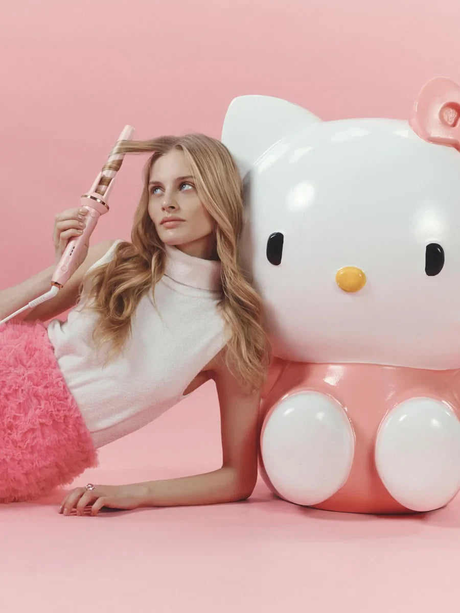 Woman with a large Hello Kitty toy on a pink background